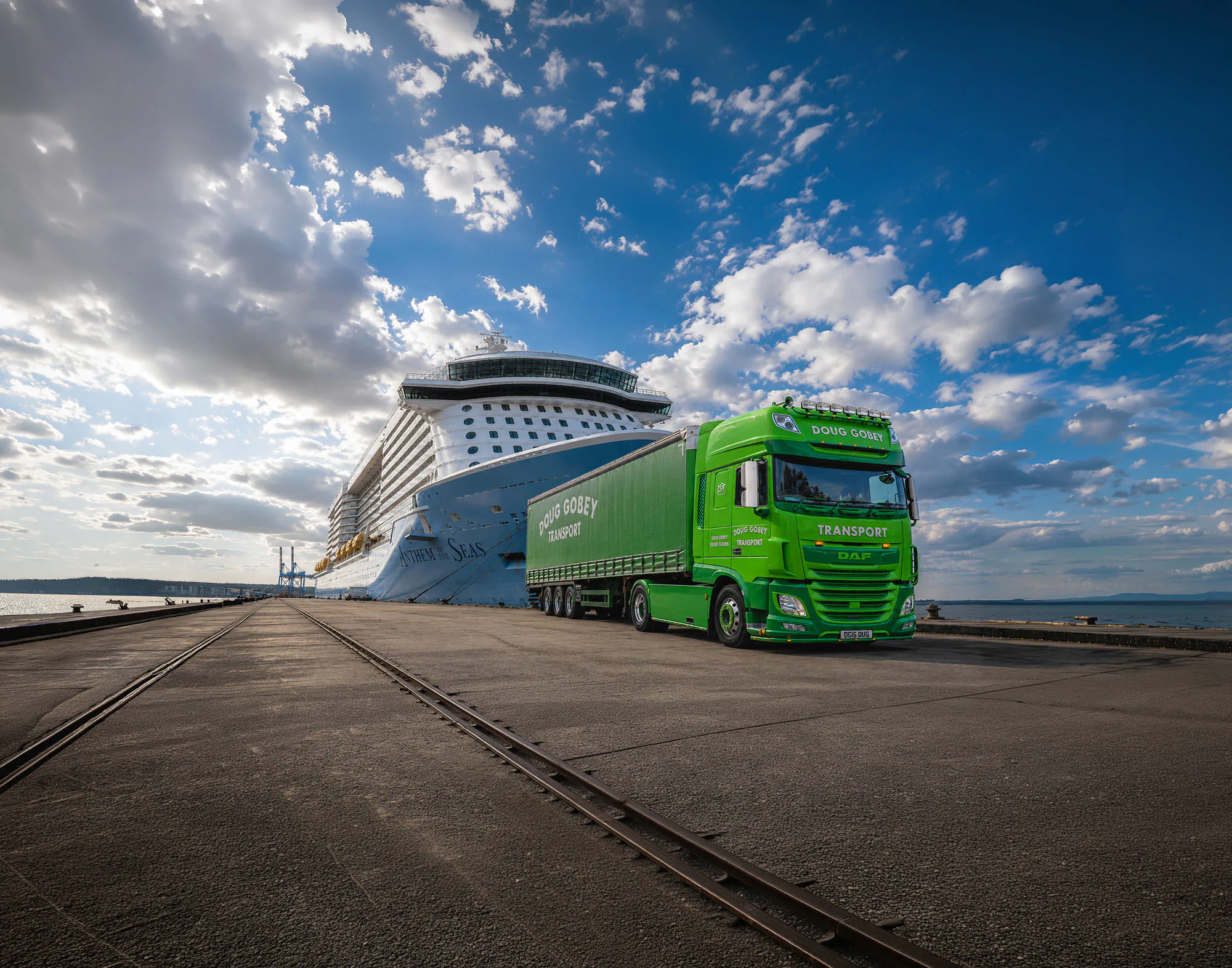 Doug Gobey Transport lorry alongside the cruise ship Anthem of the Seas at the docks, ready for onward haulage