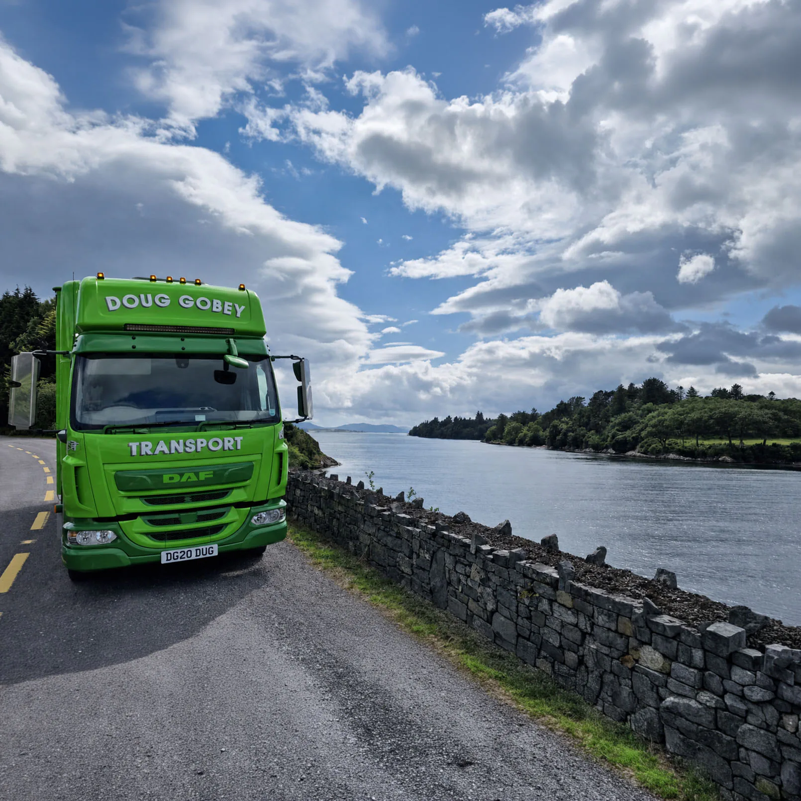 Doug Gobey Transport lorry on a coastal road beside a stone wall and loch